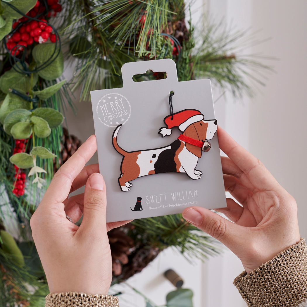 Basset Hound Christmas tree decoration held in hands on backing card — Father Christmas hat and jingle bell collar, dog lover gift by Sweet William Designs