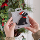 Black Cocker Spaniel Christmas tree decoration held in hands on backing card — Father Christmas hat and jingle bell collar, dog lover gift by Sweet William Designs