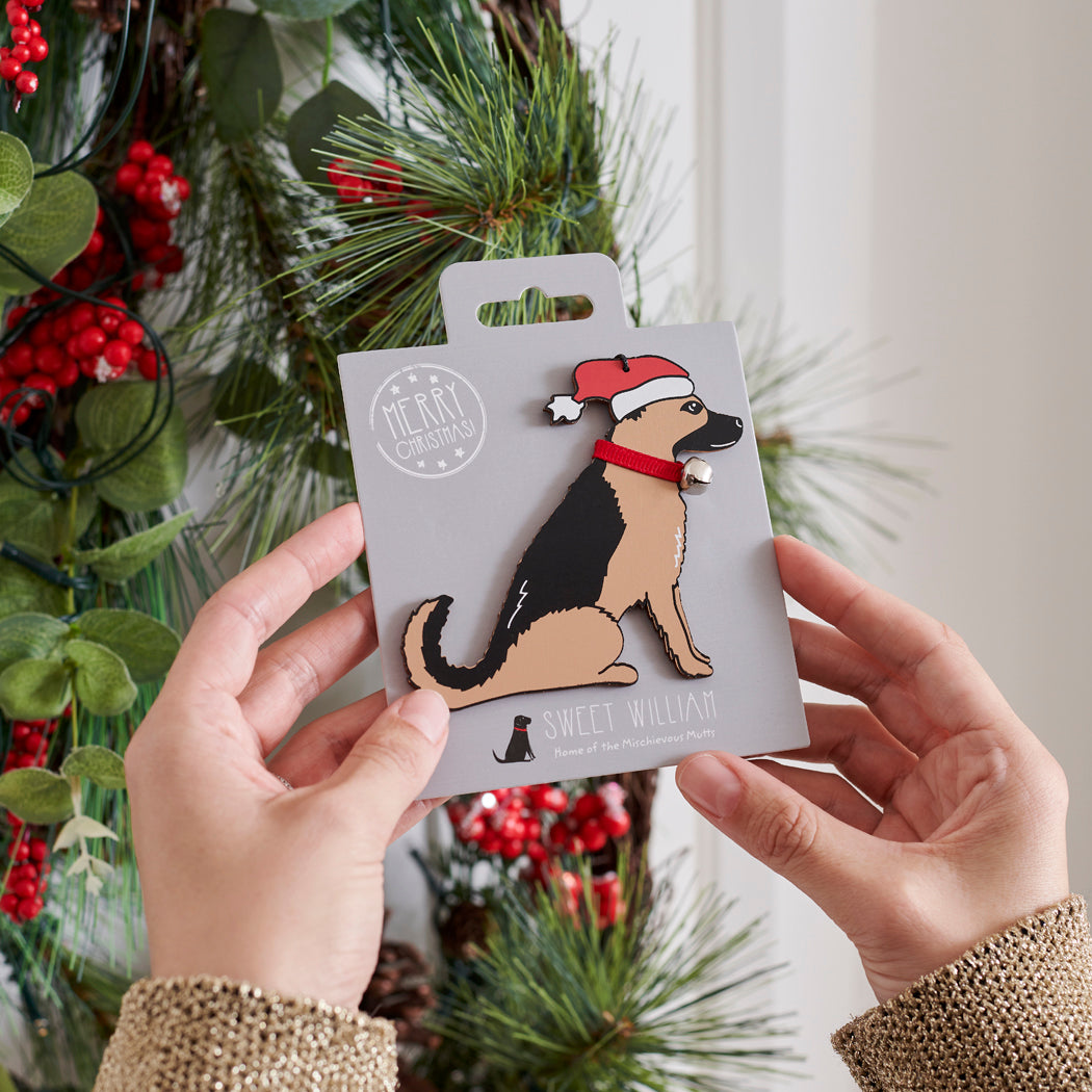German Shepherd Christmas tree decoration held in hands on backing card — Father Christmas hat and jingle bell collar, dog lover gift by Sweet William Designs