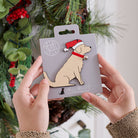 Golden Retriever Christmas tree decoration held in hands on backing card — Father Christmas hat and jingle bell collar, dog lover gift by Sweet William Designs