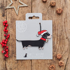 Dachshund Christmas decoration on backing card — wooden dog decoration with Father Christmas hat and jingle bell collar, festive dog lover gift by Sweet William Designs
