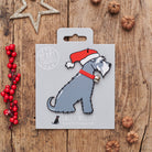 Grey Schnauzer Christmas decoration on backing card — wooden dog decoration with Father Christmas hat and jingle bell collar, festive dog lover gift by Sweet William Designs