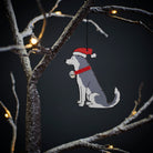 Husky Christmas tree decoration hanging on lit winter tree — wooden dog decoration with Father Christmas hat and jingle bell collar by Sweet William Designs