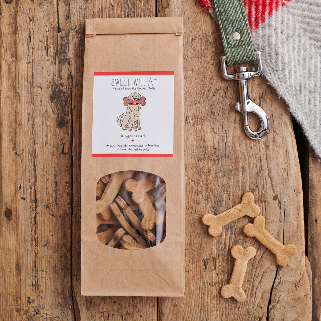 Gingerbread Dog Treats in kraft packaging with bone-shaped biscuits on rustic wooden surface — handmade natural dog treats by Sweet William Designs