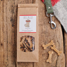 Gingerbread Dog Treats in kraft packaging with bone-shaped biscuits on rustic wooden surface — handmade natural dog treats by Sweet William Designs