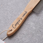 Close-up of personalised bamboo dog comb handle engraved with 'Cooper's comb' in script — metal-tooth grooming comb, dog lover gift by Sweet William Designs