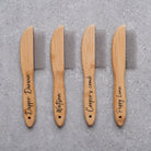 Four personalised bamboo dog combs with metal teeth laid in a row, engraved with dog names — Dapper Darwin, Watson, Cooper's comb and Puppy Luna — by Sweet William Designs