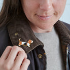 Close-up of Basset Hound enamel pin being attached to a corduroy jacket collar — gold-plated dog pin by Sweet William Designs
