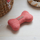 Close-up of the orange tweed dog bone toy with its Sweet William label, styled beside a Golden Retriever dog bowl and matching lead