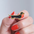 Close-up of a Dachshund enamel pin held in hand, showing the detailed Dachshund dog design by Sweet William Designs