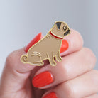 Close-up of a Pug enamel pin held in hand, showing the detailed Pug illustration by Sweet William Designs