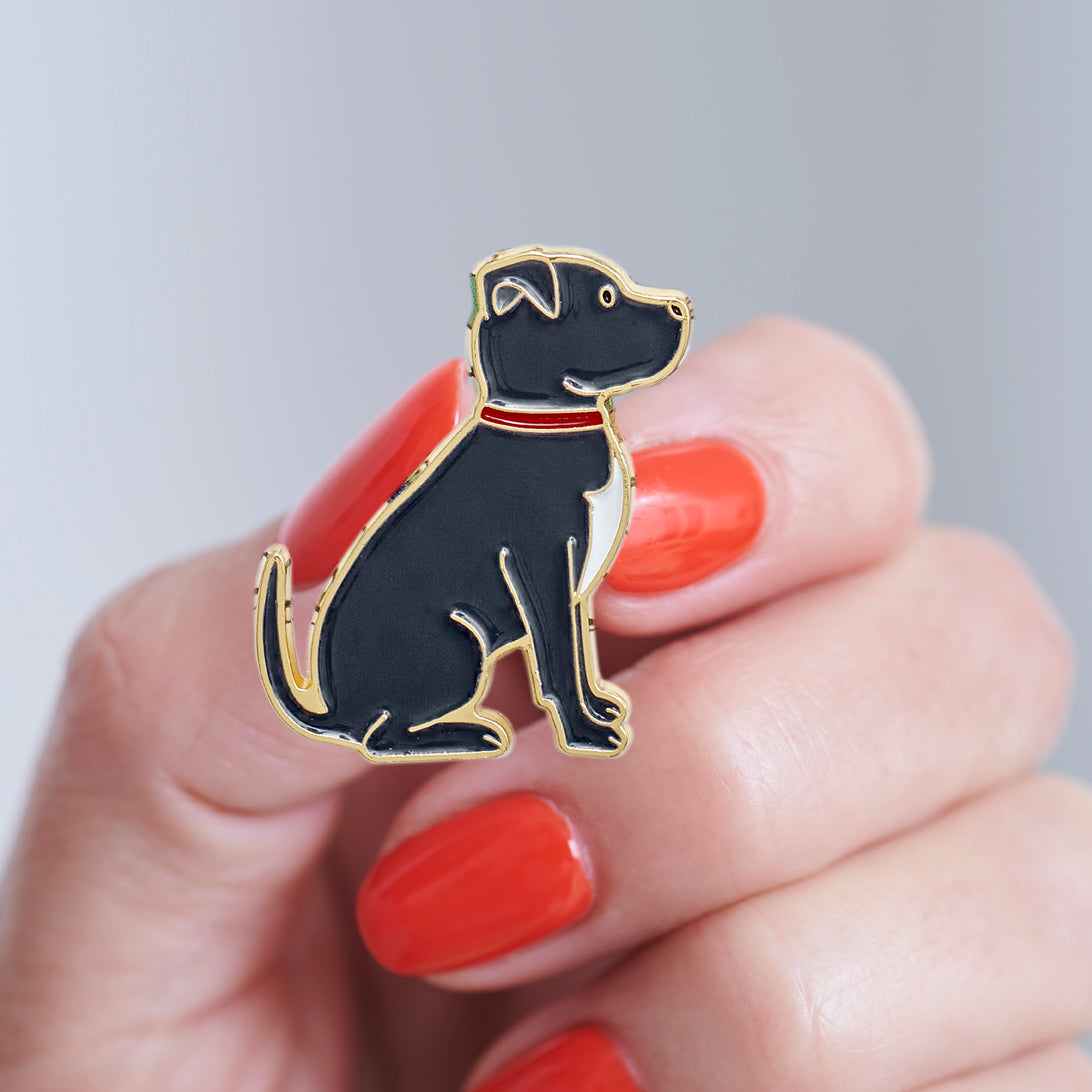 Close-up of a Staffie enamel pin held in hand, showing the detailed Staffie illustration by Sweet William Designs