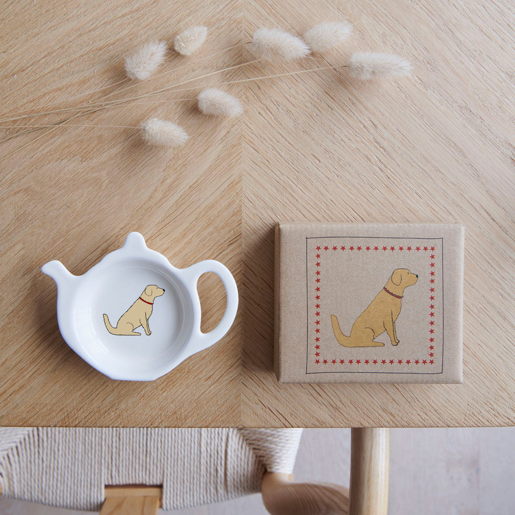 White teapot-shaped Golden Retriever teabag dish beside its kraft gift box, both featuring a golden dog illustration with a red collar