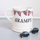 Ceramic Gramps mug with hand-drawn Union Jack bunting and two small black toy cars, a thoughtful gift for a much-loved grandfather