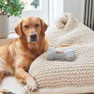 Golden Retriever relaxing beside our grey tweed dog bone toy on a chunky white blanket