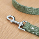 Close-up of the silver clasp on a green tweed dog lead