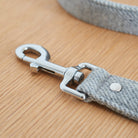 Close-up of the silver clasp on a grey tweed dog lead