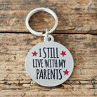 Close-up of 'I Still Live With My Parents' dog tag — silver-plated brass with red star design, personalised dog ID tag by Sweet William Designs