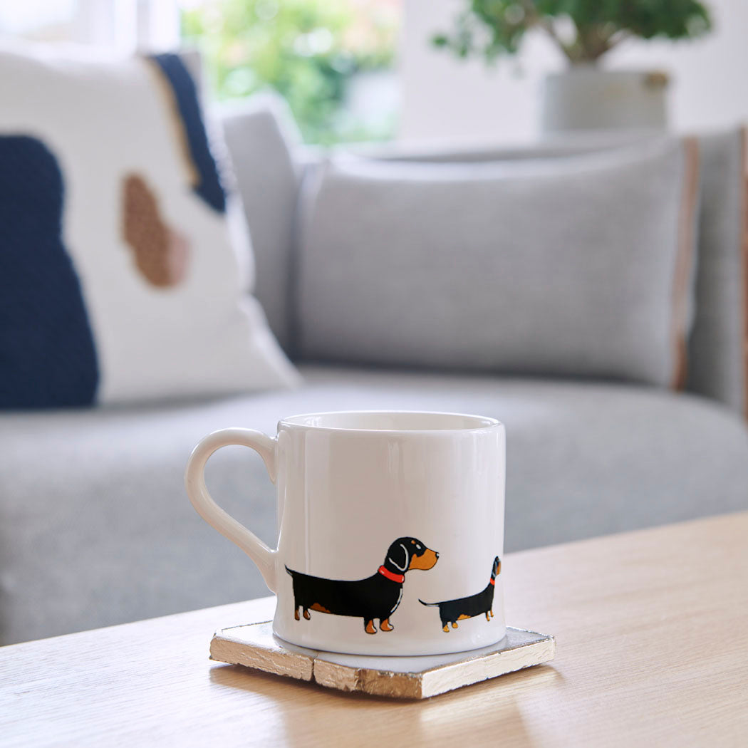 Sweet William Dachshund Mug on a coffee table — illustrated Dachshund repeat pattern ceramic mug