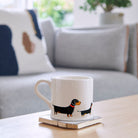 Sweet William Dachshund Mug on a coffee table — illustrated Dachshund repeat pattern ceramic mug