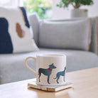 Sweet William Lurcher Mug on a coffee table — illustrated Lurcher repeat pattern ceramic mug