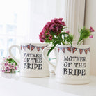 Father of the Bride and Mother of the Bride ceramic mugs shown side by side with flowers, a lovely keepsake gift for the bride’s parents