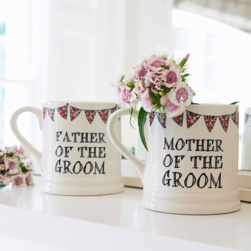Father of the Groom and Mother of the Groom ceramic mugs shown side by side with flowers, a lovely keepsake gift for the groom’s parents