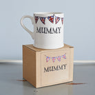 Ceramic Mummy mug with hand-drawn Union Jack bunting, displayed on its kraft gift box as a thoughtful gift for Mum