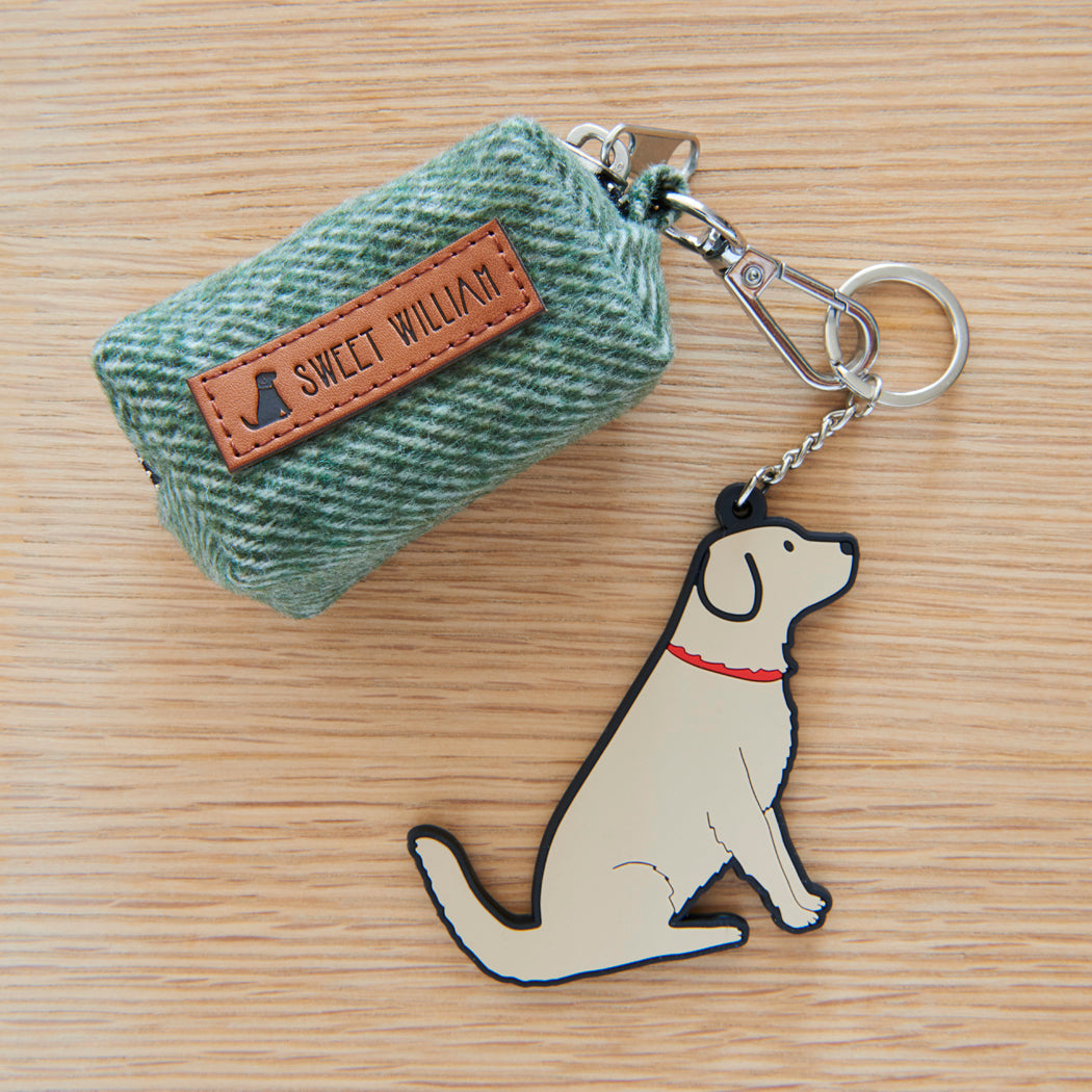 Close-up of the green tweed poo bag holder with its Sweet William label, clip and golden retriever keyring