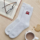 Crab wool socks laid flat with book, glasses and cup of tea — embroidered wool blend coastal socks, thoughtful seaside gift