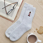 Lighthouse wool socks laid flat with book, glasses and cup of tea — embroidered wool blend coastal socks, thoughtful seaside gift