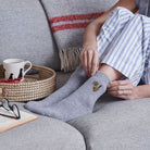 Woman putting on Carrots & Trowel gardening socks on sofa — cosy wool blend socks, perfect gift for gardeners by Sweet William Designs