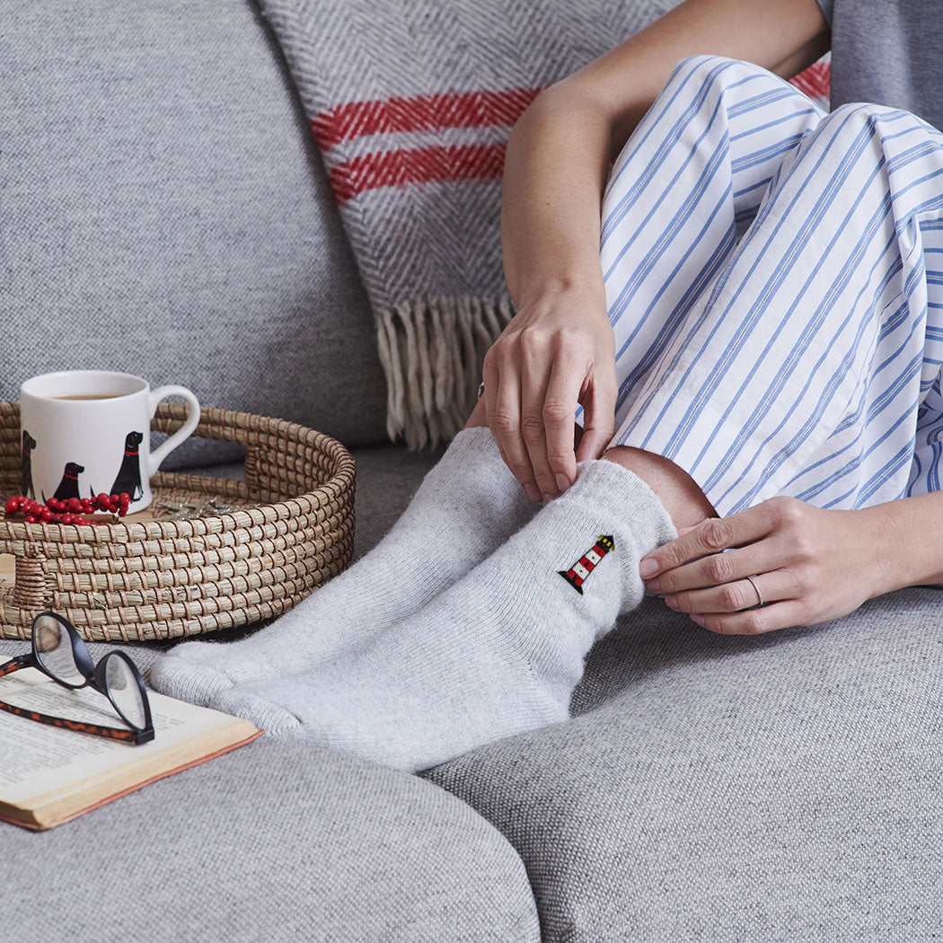 Woman relaxing on sofa in lighthouse wool socks — cosy embroidered wool blend socks, perfect gift for coastal lovers by Sweet William Designs
