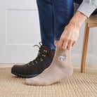 Man pulling on sheep wool socks with walking boots indoors — unisex embroidered wool blend socks by Sweet William Designs