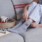 Woman relaxing on the sofa putting on embroidered golf buggy wool socks — soft golf sports socks, an ideal gift for golf fans
