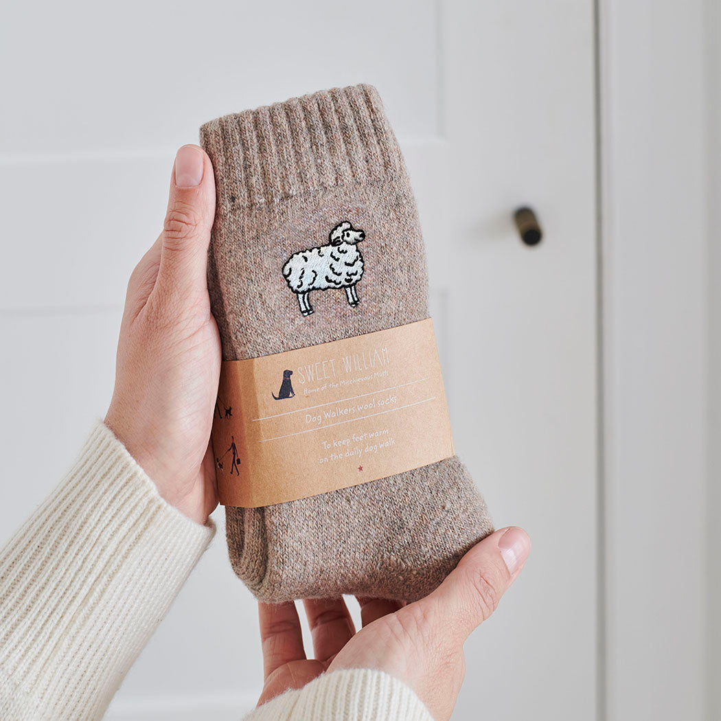 Sheep wool socks held in hands with Sweet William Designs branded band — soft wool blend sheep lover gift
