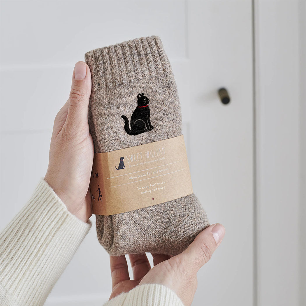 Black cat wool socks held in hands with Sweet William Designs branded band — soft wool blend cat lover gift