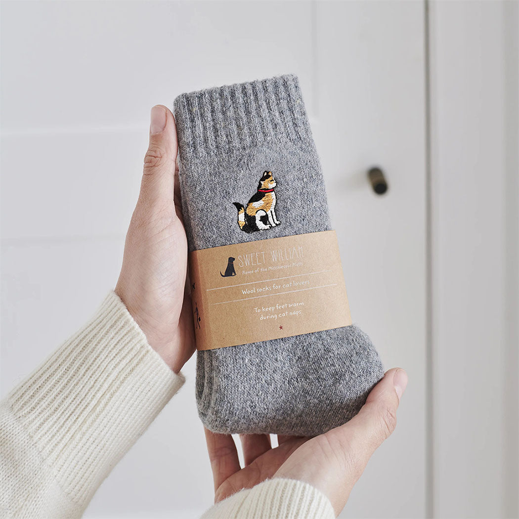 Tortoiseshell cat wool socks held in hands with Sweet William Designs branded band — soft wool blend cat lover gift