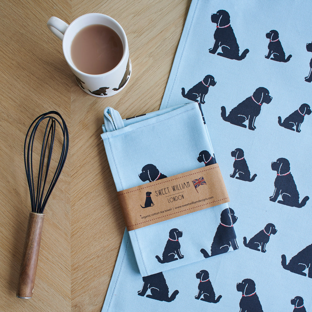 Organic cotton Black Cockapoo / Labradoodle tea towel on a wooden table with a matching mug — organic cotton screen printed kitchen gifts for dog lovers by Sweet William Designs.