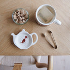 White teapot-shaped Liver & White Springer Spaniel teabag dish with a dog illustration and red collar, beside a mug, sugar cubes and sugar tongs