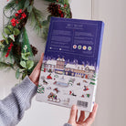 Back of the Christmas Dog Treat Advent Calendar held in a hand, showing product information for natural grain-free dog treats baked in Lincolnshire, England