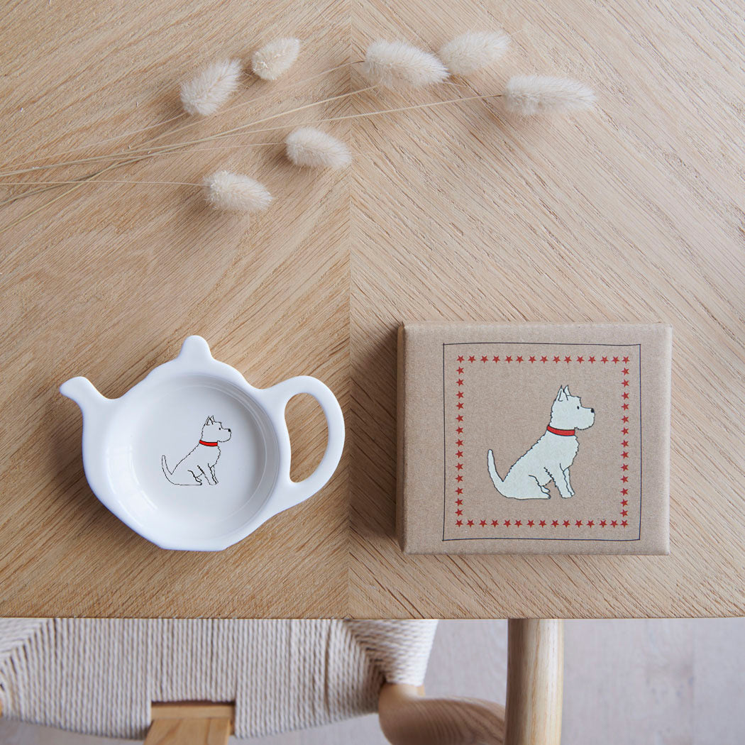 White teapot-shaped Westie teabag dish beside its kraft gift box, both featuring a West Highland White Terrier illustration with a red collar