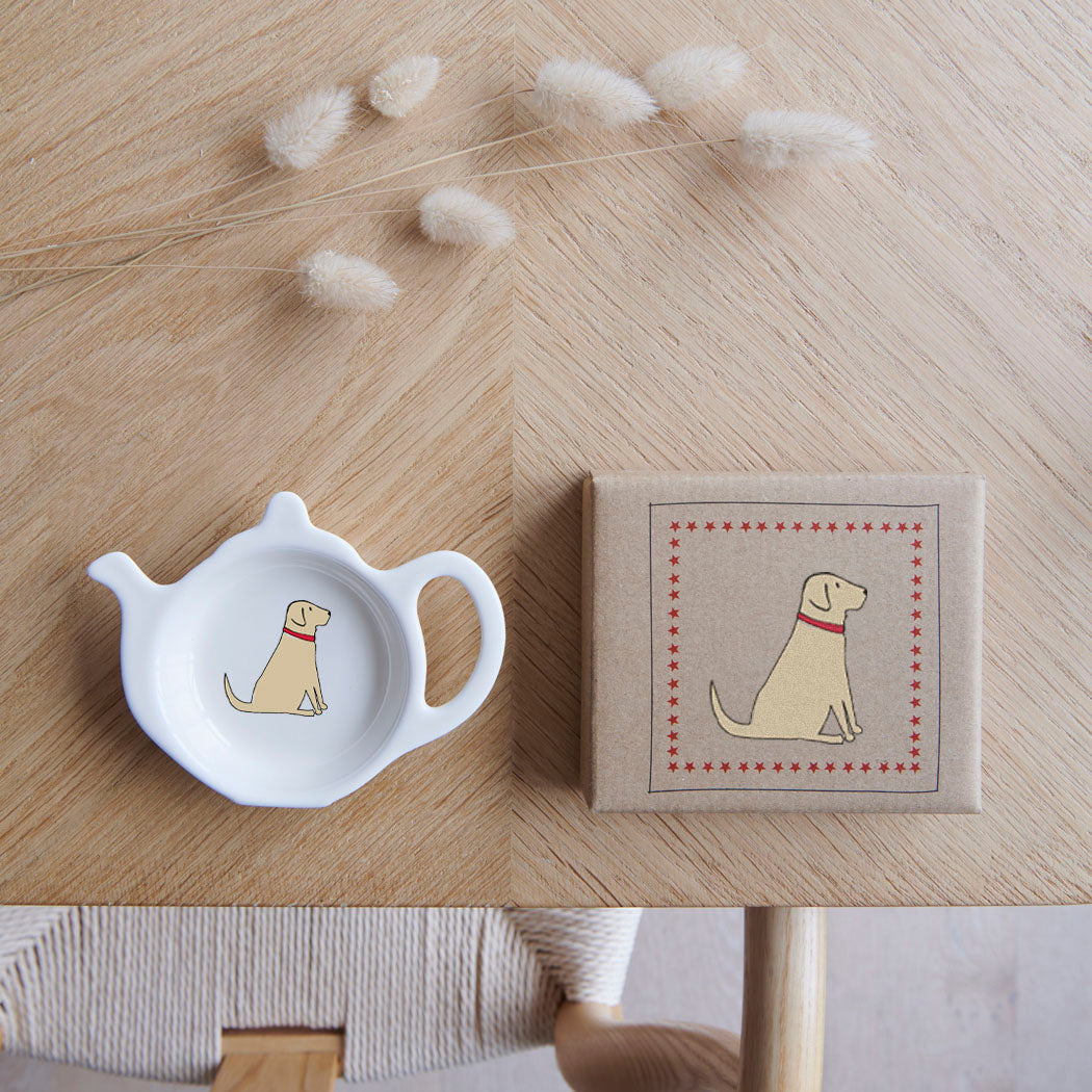 White teapot-shaped Yellow Labrador teabag dish beside its kraft gift box, both featuring a Yellow Lab illustration with a red collar