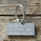 Reverse of personalised Dachshund dog tag engraved with phone number and address on rustic wood — practical and personalised dog ID tag gift