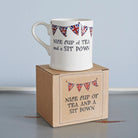 Ceramic mug with Union Jack bunting and a “Nice cup of tea and a sit down” message displayed on its gift box, a perfect gift for tea lovers