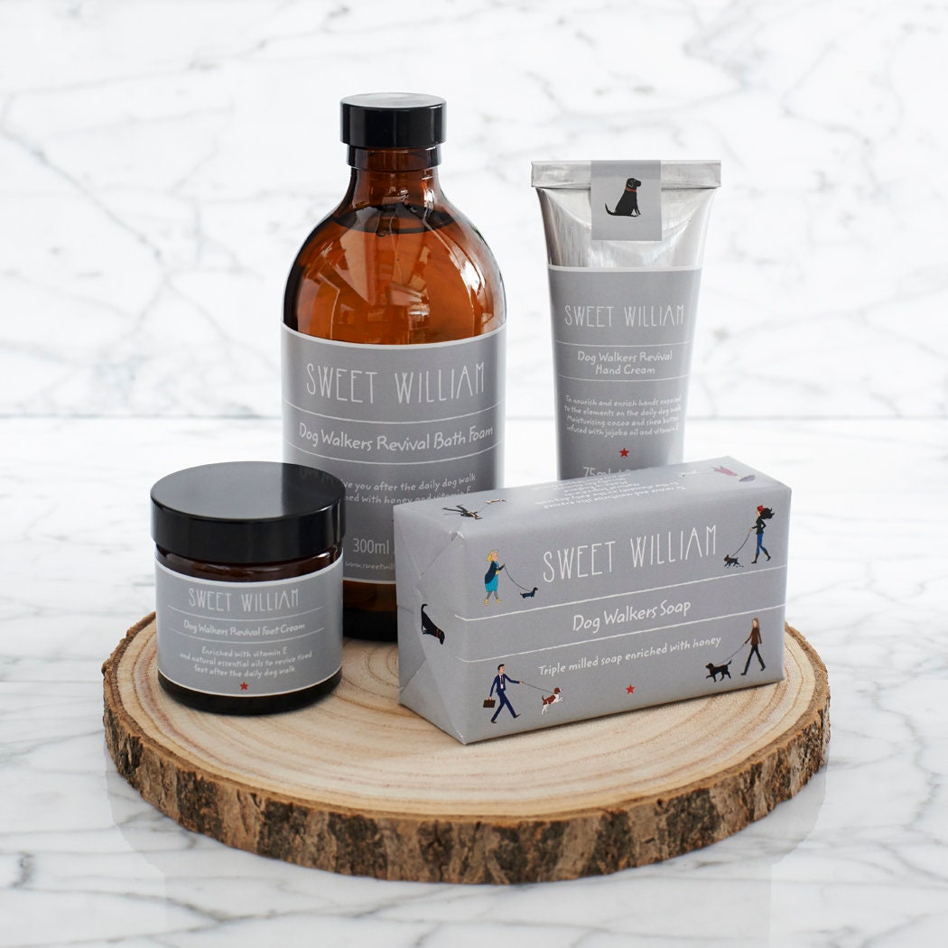 Dog Walkers Revival Collection displayed on a round wooden board, including bath foam, soap, foot cream and hand cream — dog lover gift by Sweet William Designs