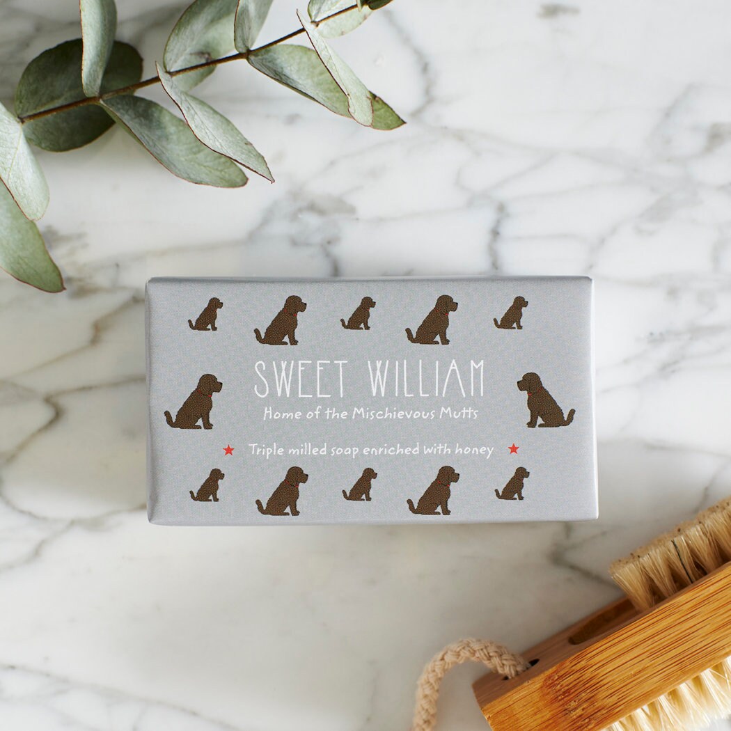 Close-up of Chocolate Cockapoo / Labradoodle soap packaging — Sweet William triple milled soap enriched with honey, featuring an illustrated Chocolate Cockapoo / Labradoodle repeat pattern
