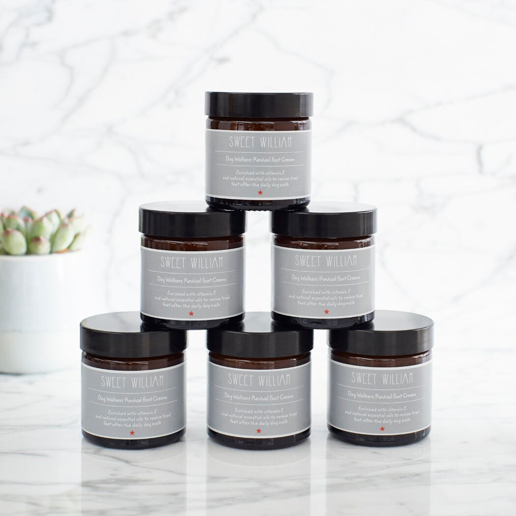 Six jars of Dog Walkers Revival Foot Cream stacked in a pyramid on marble surface — dog lover gift by Sweet William Designs