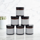Six jars of Dog Walkers Revival Foot Cream stacked in a pyramid on marble surface — dog lover gift by Sweet William Designs