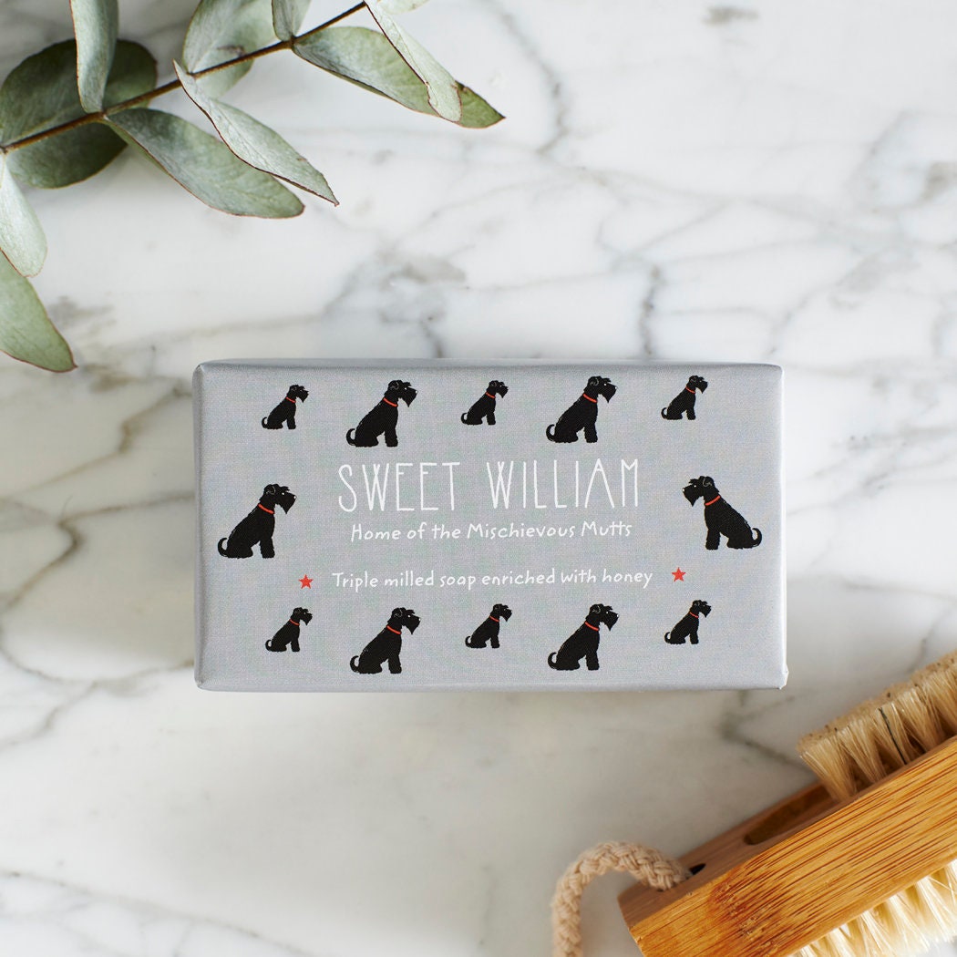 Close-up of Black Schnauzer soap packaging — Sweet William triple milled soap enriched with honey, featuring an illustrated Black Schnauzer repeat pattern
